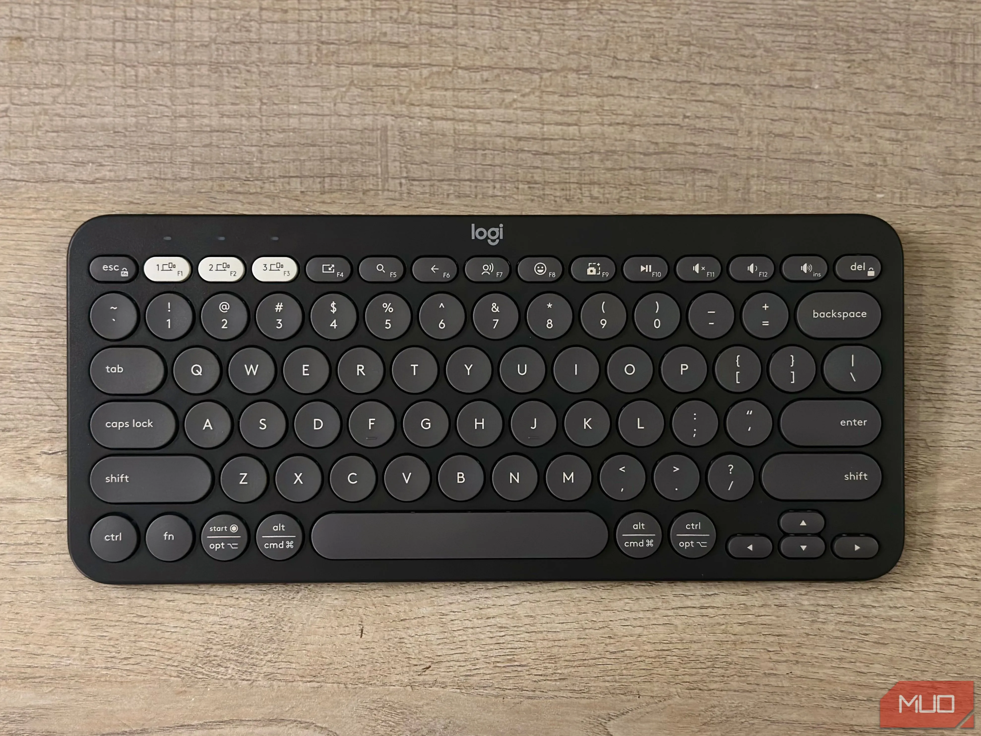 Bàn phím không dây Logitech Pebble Keys 2 K380s màu trắng đặt trên mặt bàn gỗ