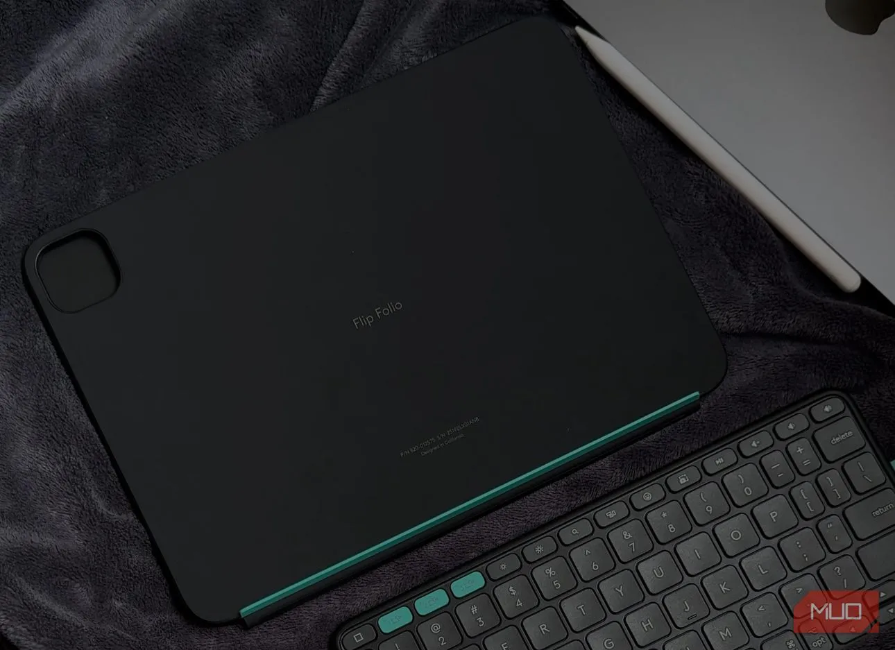 Bàn phím Logitech Flip Folio được đặt trên chăn cạnh iPad, minh họa các phím tắt iPadOS chuyên dụng và khả năng sử dụng linh hoạt ở nhiều môi trường.