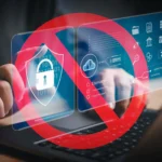 Bàn tay đang gõ laptop với dấu cấm màu đỏ che biểu tượng bảo mật, minh họa nguy cơ lộ mật khẩu và tầm quan trọng của bảo mật thông tin cá nhân.