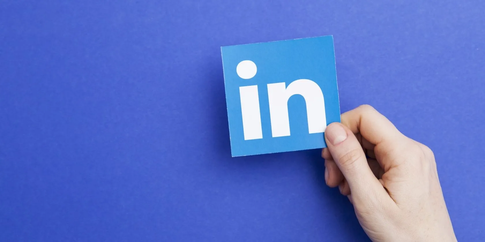 Biểu tượng LinkedIn &quot;in&quot; trên tay, minh họa mạng xã hội chuyên nghiệp này thu thập dữ liệu người dùng để đào tạo AI và chia sẻ với bên thứ ba.