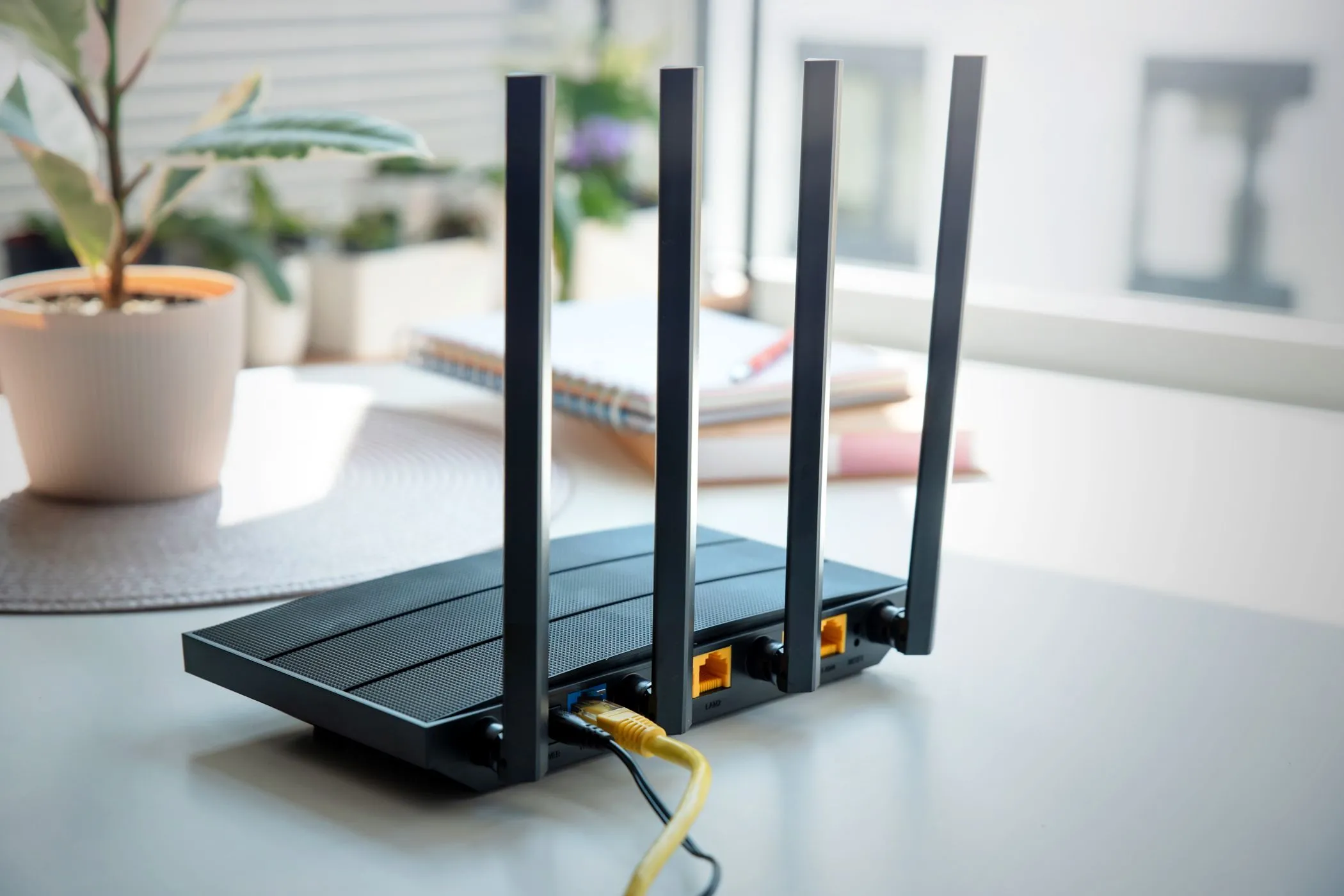 Bộ định tuyến Wi-Fi với bốn ăng-ten đặt trên bàn, tượng trưng cho việc quản lý và tối ưu hóa cài đặt mạng