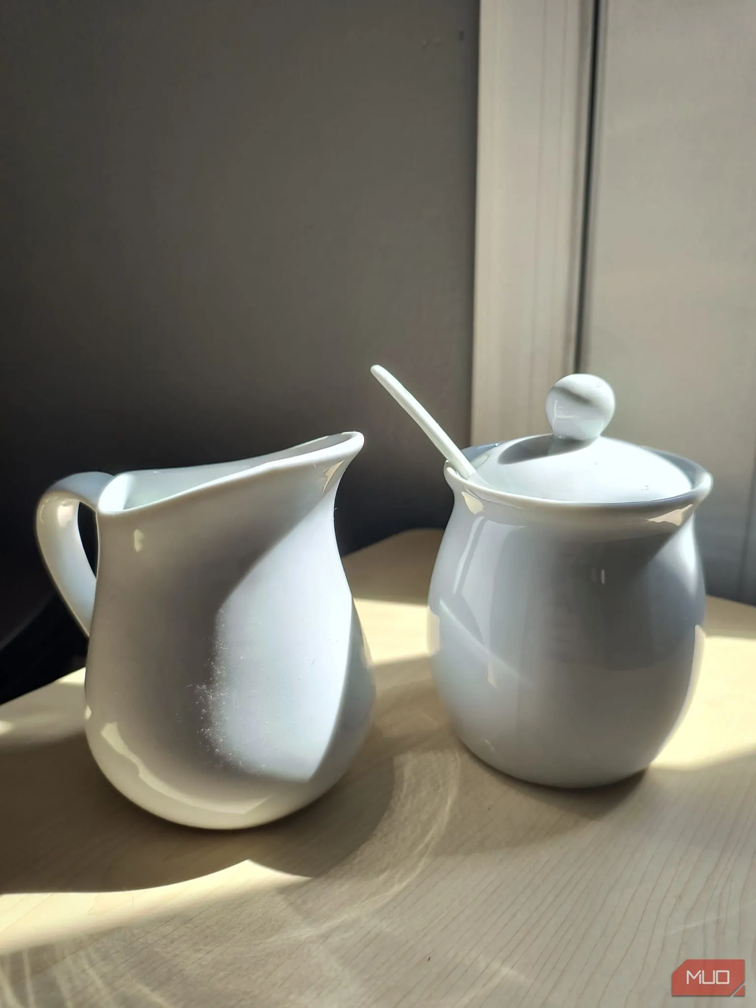 Bộ đồ đựng đường và kem bằng gốm trắng đặt dưới ánh nắng trực tiếp, HDR bật