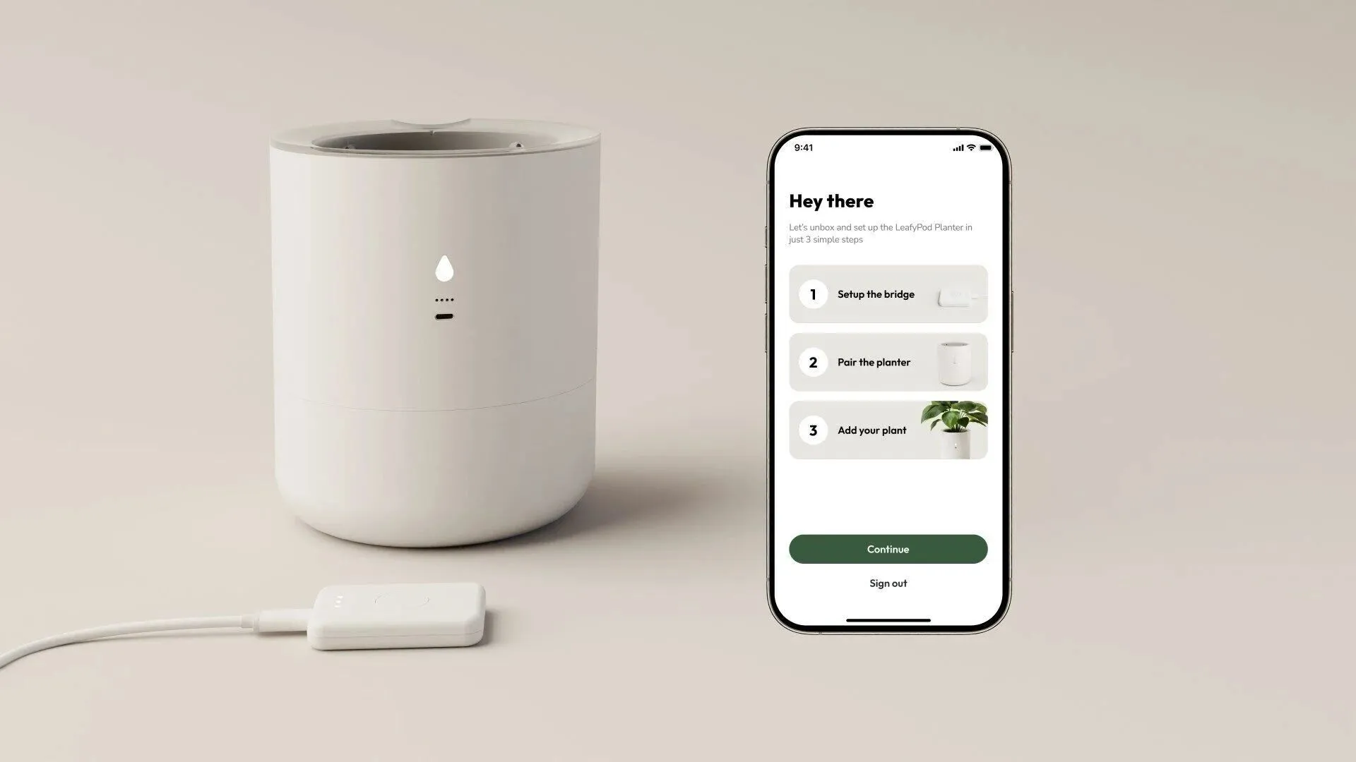 Chậu cây thông minh LeafyPod có màu trắng, đặt cạnh một chiếc điện thoại hiển thị ứng dụng với các chỉ số về sức khỏe của cây trồng.