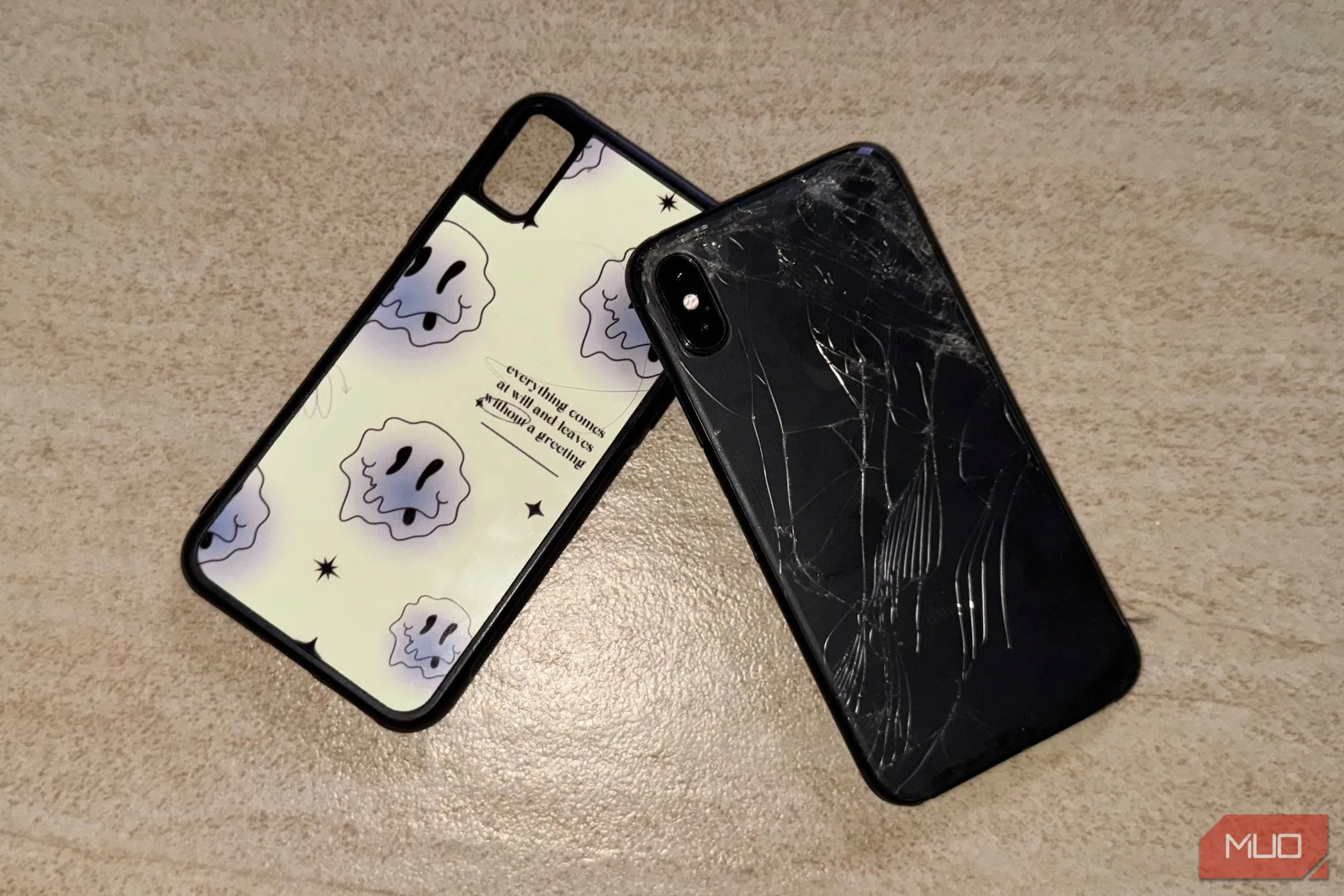 Chiếc iPhone X bị vỡ mặt lưng kính nằm trên sàn nhà cùng với ốp lưng.