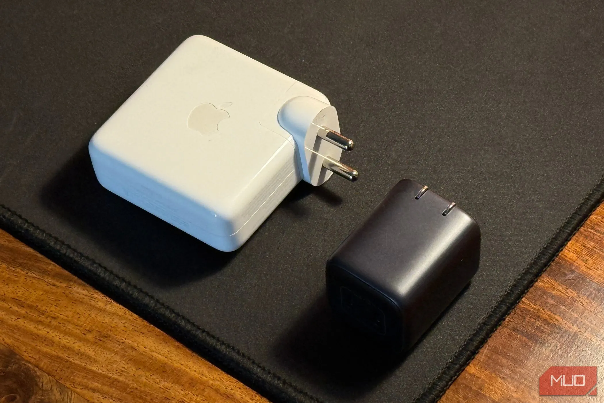 Củ sạc điện thoại nhỏ gọn đặt cạnh adapter MacBook lớn, minh họa sự khác biệt về kích thước và công suất