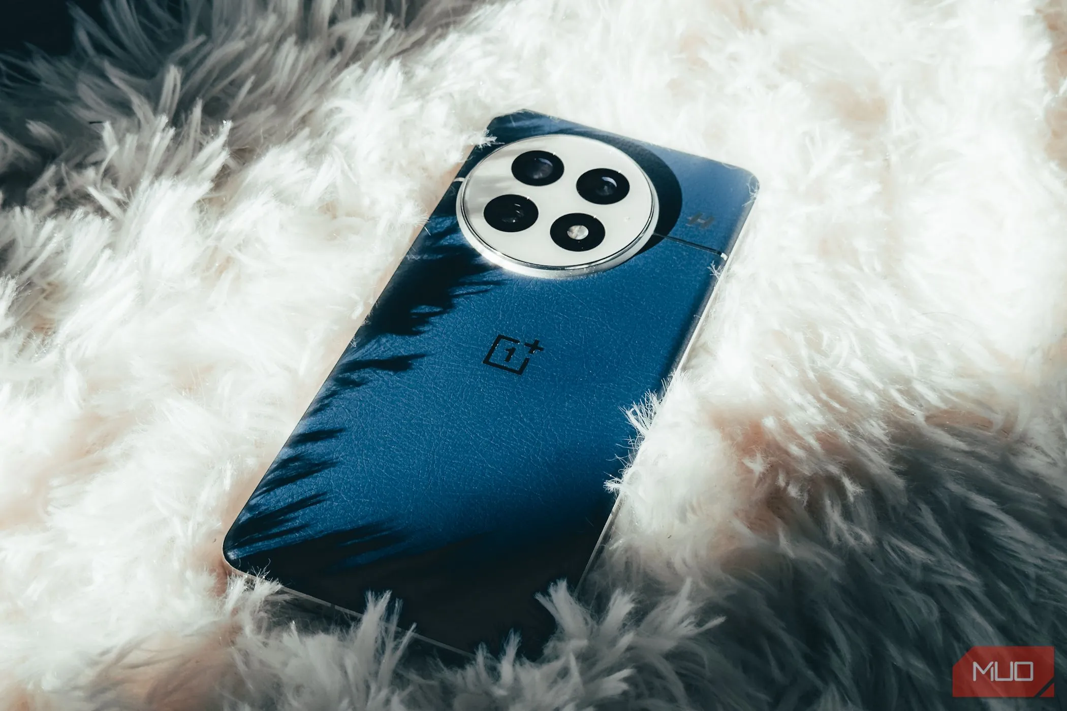 Điện thoại OnePlus 13 màu Midnight Ocean đặt trên thảm trắng, làm nổi bật thiết kế và chất liệu vegan leather