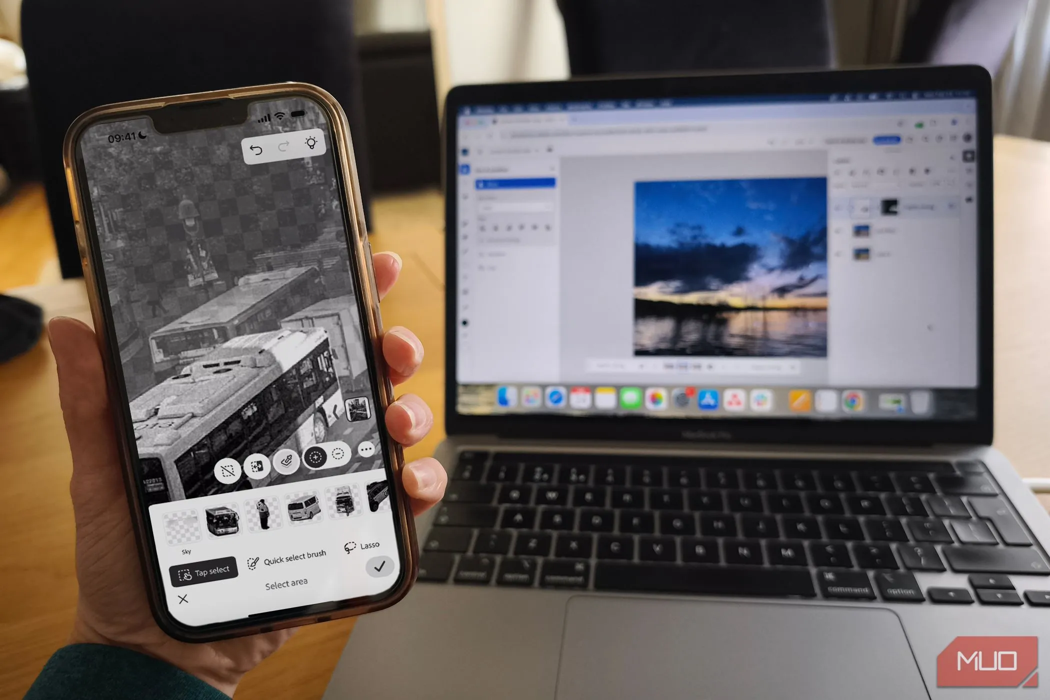 Giao diện ứng dụng Photoshop Mobile và phiên bản Photoshop trên nền web hiển thị trên MacBook, minh họa sự kết nối linh hoạt giữa các nền tảng.