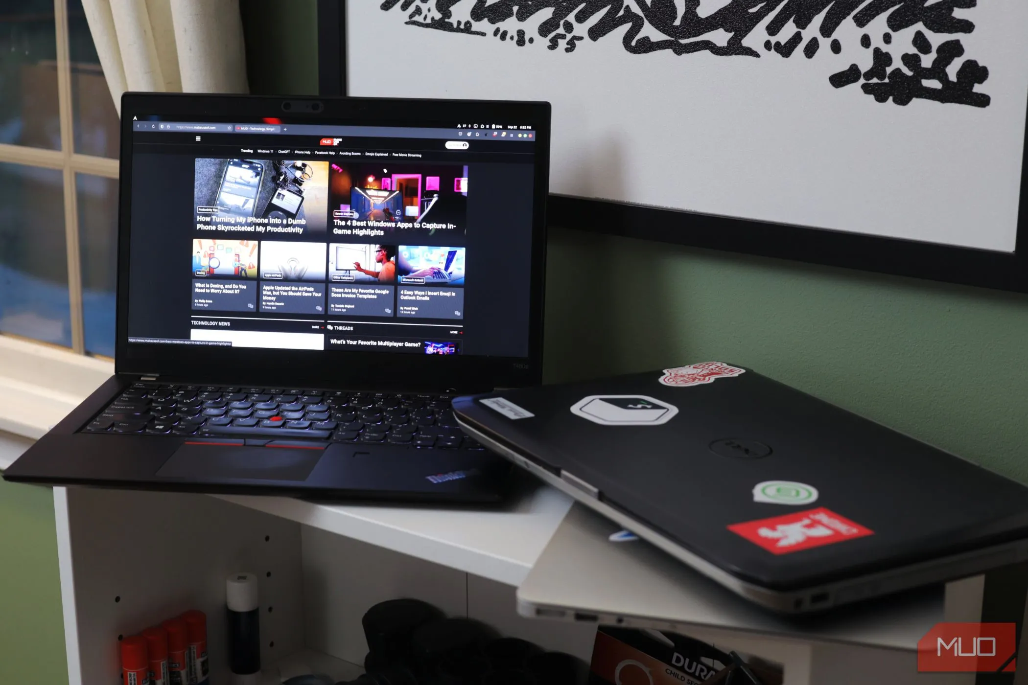 Hai chiếc laptop trên kệ trắng, một chiếc mở ra trang web, biểu trưng cho việc không nên chia sẻ thiết bị để bảo mật.