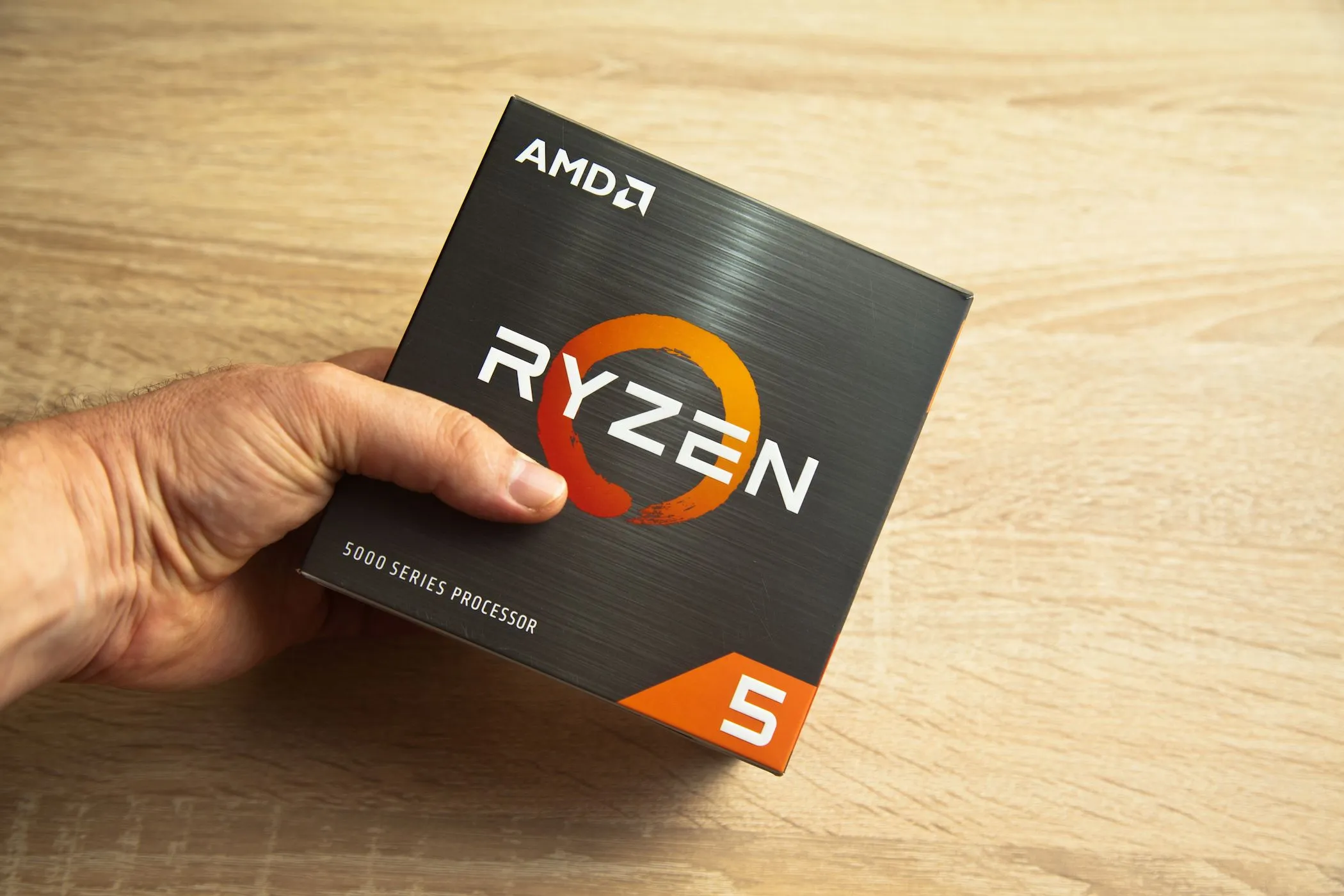 Hình ảnh một người đàn ông cầm hộp bộ vi xử lý AMD Ryzen 5, nhấn mạnh tầm quan trọng của CPU trong laptop giá rẻ