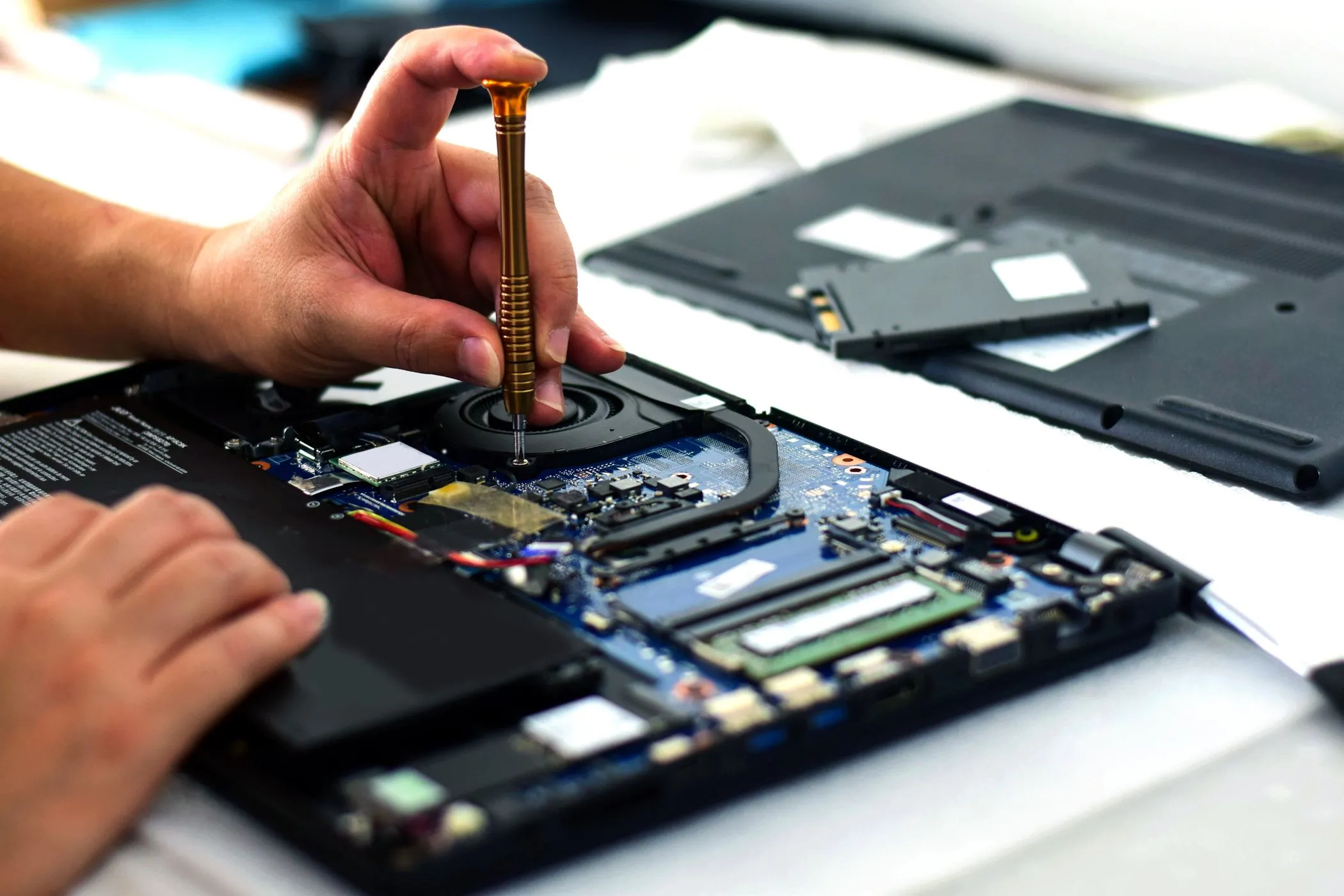 Kỹ thuật viên đang sửa chữa bo mạch chủ laptop, minh họa sự phức tạp và khó khăn khi sửa chữa laptop mỏng nhẹ.