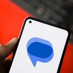 Logo ứng dụng Google Messages hiển thị trên màn hình điện thoại Android, có bàn phím ảo ở phía sau