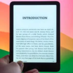 Máy đọc sách Amazon Kindle Paperwhite Signature Edition đặt trước màn hình máy tính, minh họa cho việc cập nhật và trải nghiệm tính năng Kindle Recaps mới.