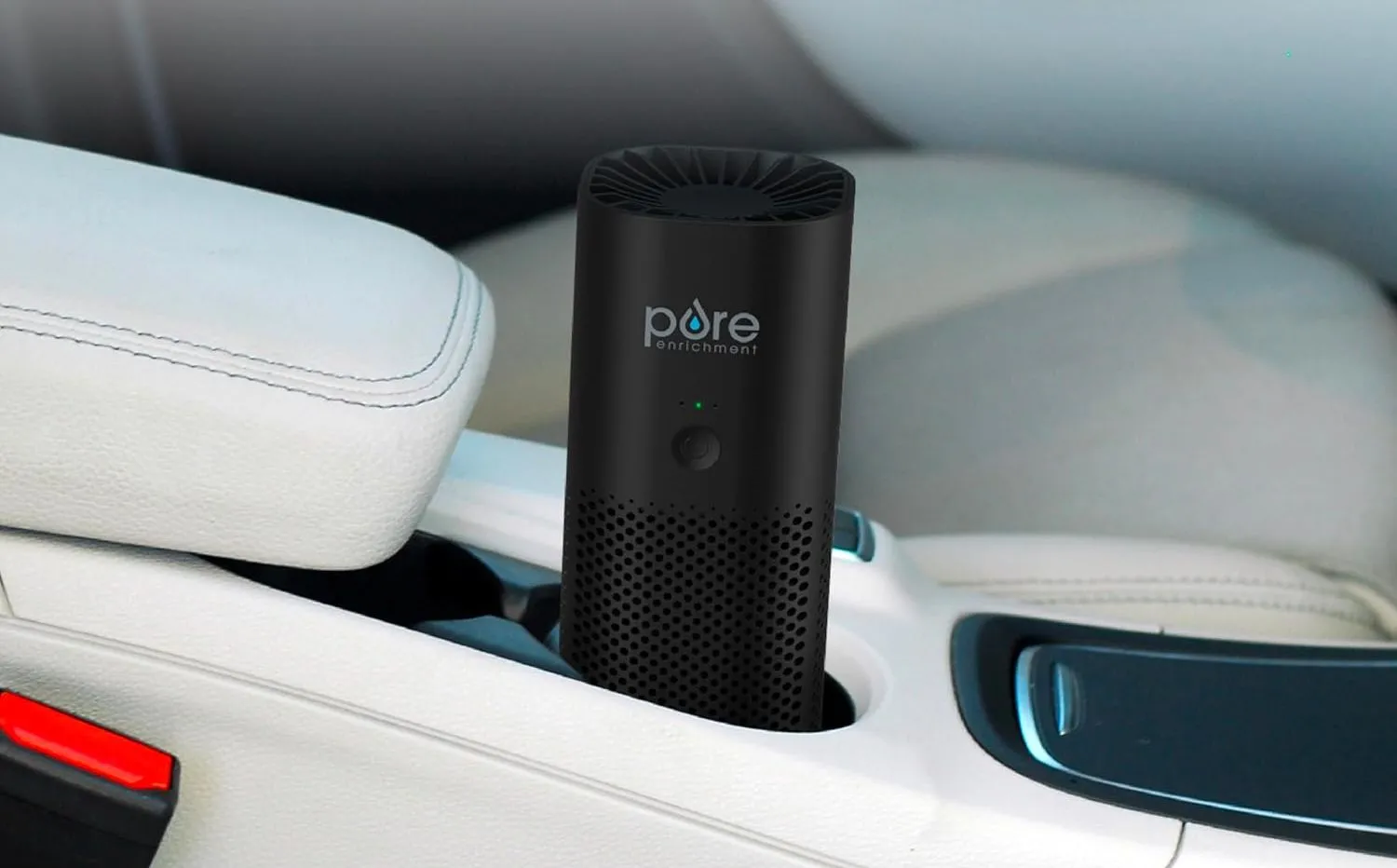 Máy lọc không khí PureZone Mini cầm tay màu trắng đặt trong hốc để cốc của ô tô.