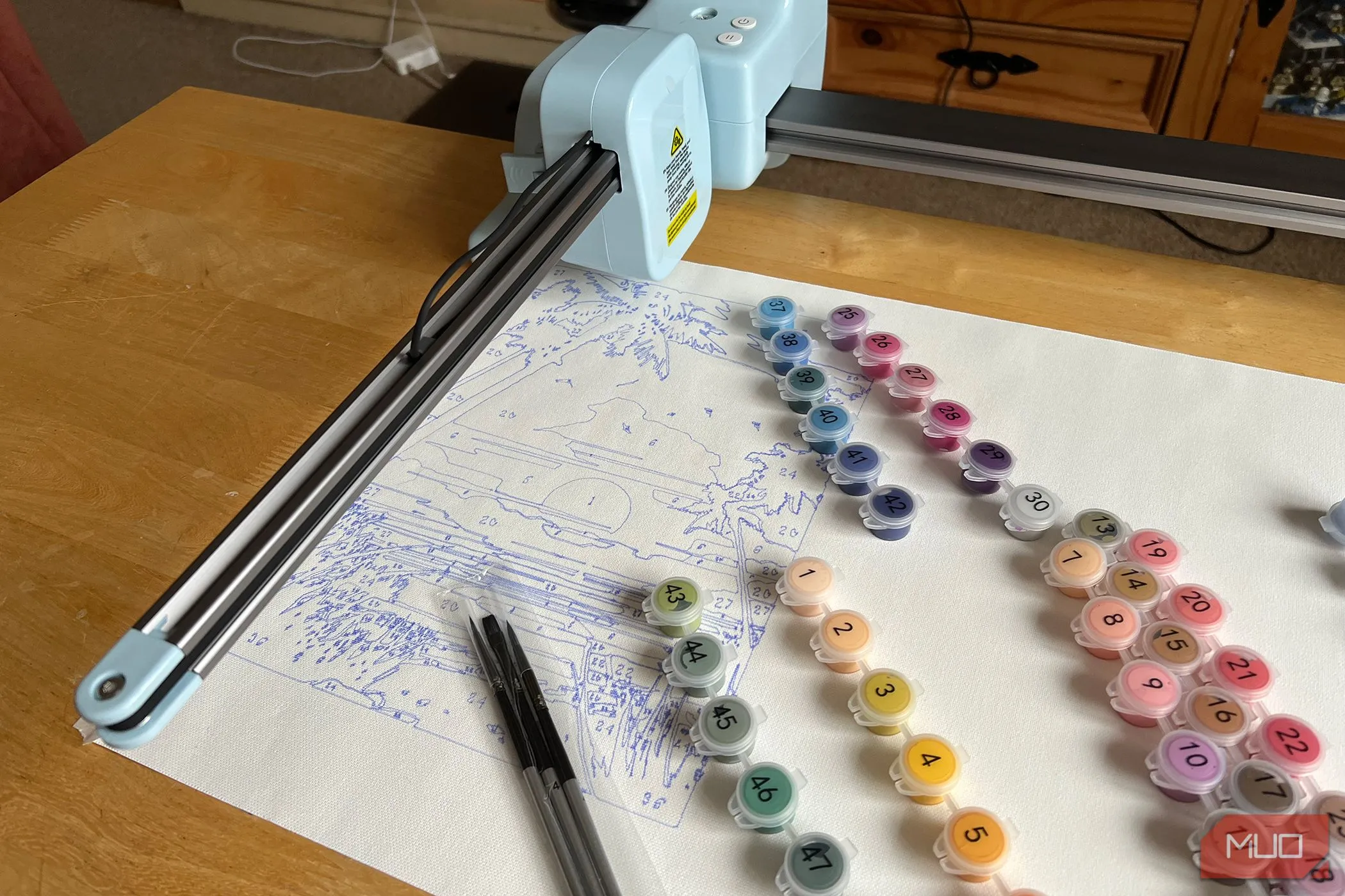 Máy LOKLiK iPaint với bức tranh phong cảnh hoàng hôn đang được vẽ và các hộp màu đi kèm