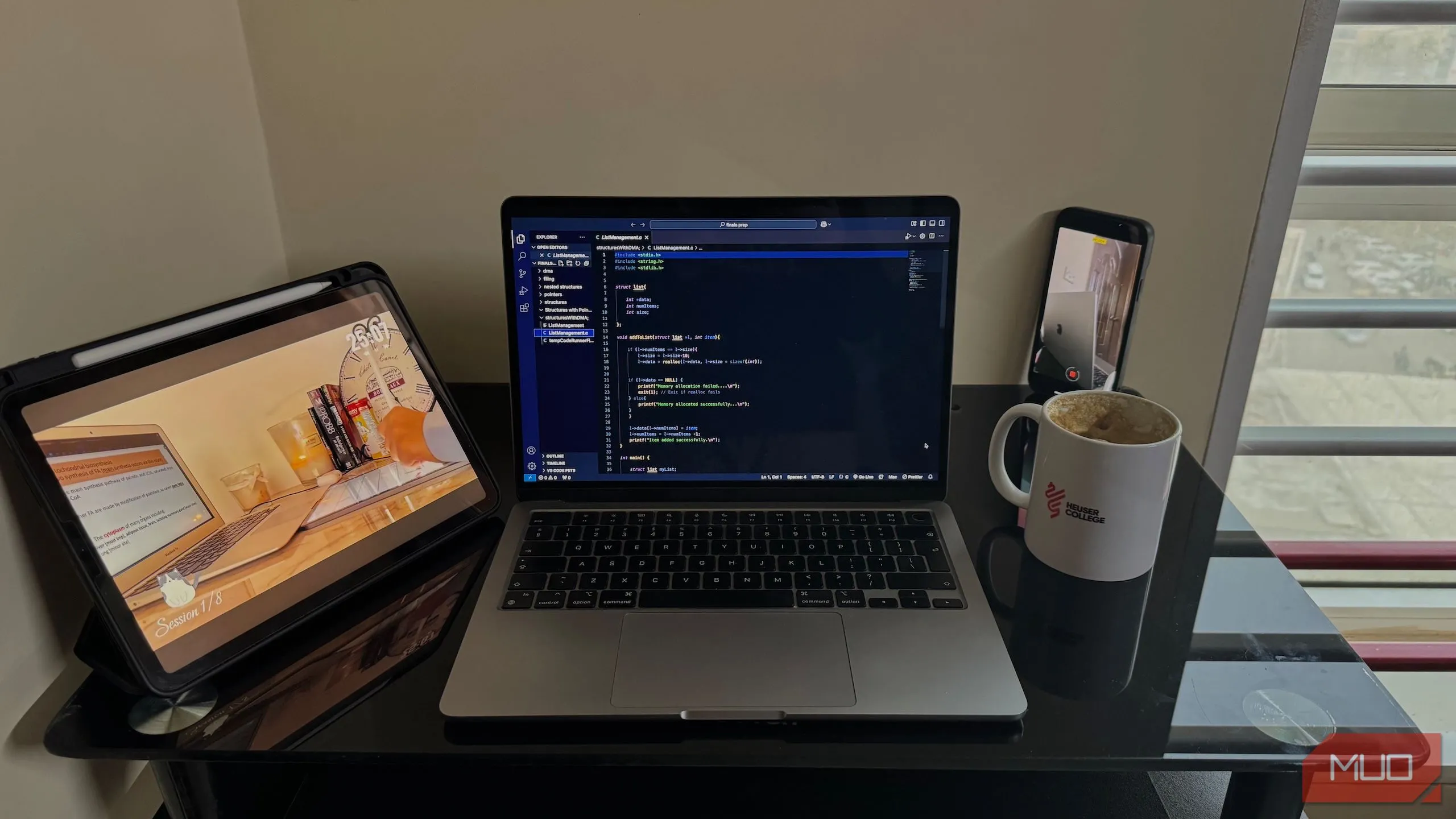 Máy tính MacBook, iPad và điện thoại đặt trên bàn làm việc gọn gàng.