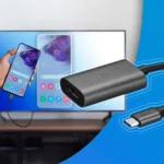 Một bàn tay đang cầm điện thoại kết nối với màn hình lớn thông qua bộ chuyển đổi USB-C sang HDMI.