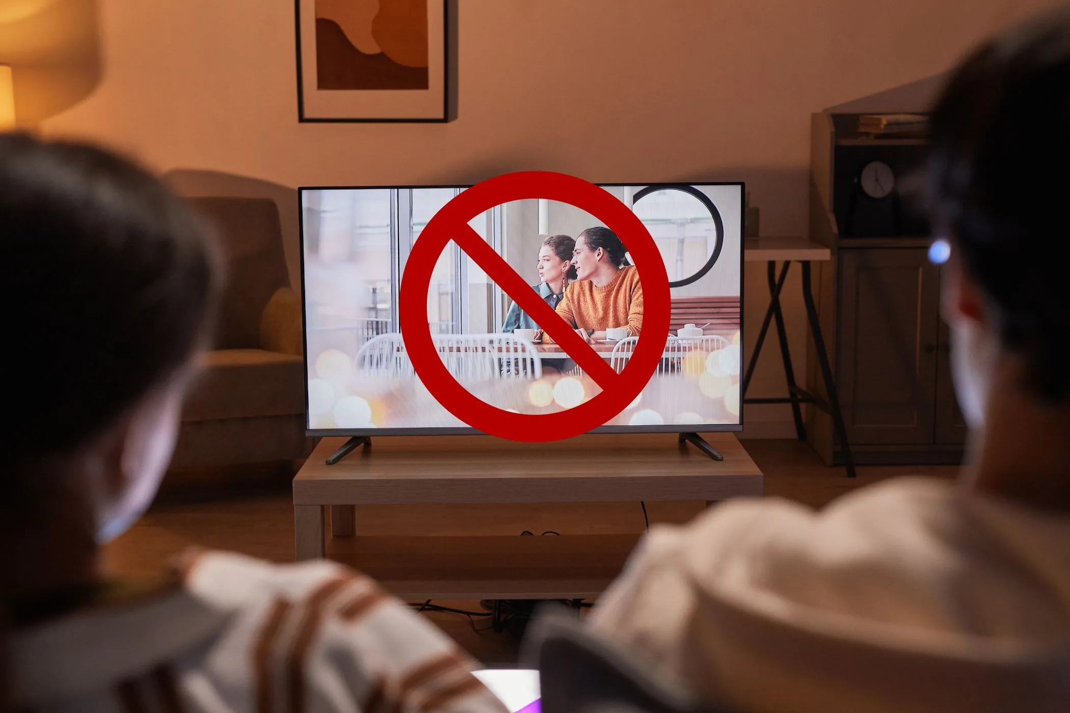 Một cặp đôi đang xem TV với một vòng tròn gạch chéo trên màn hình, biểu tượng cho việc tắt tính năng theo dõi