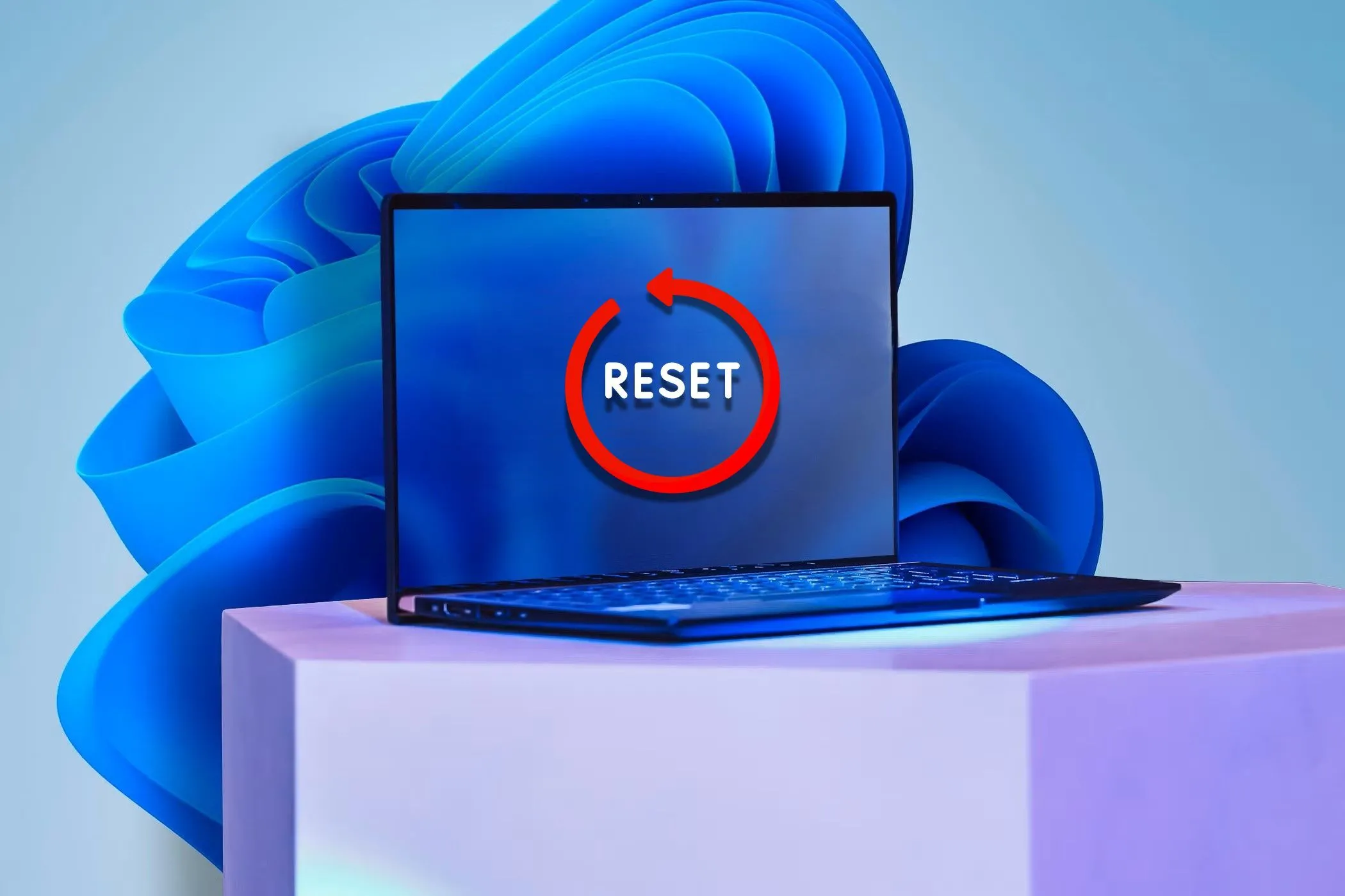 Một chiếc laptop có nhãn 'Reset' trên màn hình và hình nền Windows 11