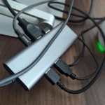 Một dock USB-C đứng với nhiều cáp kết nối được sắp xếp gọn gàng phía sau, cho thấy không gian làm việc sạch sẽ