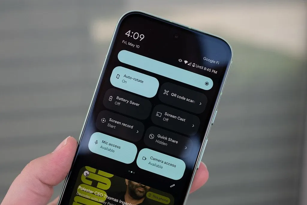 Một người đang cầm điện thoại Google Pixel 8a hiển thị cài đặt nhanh, tượng trưng cho việc sử dụng điện thoại hàng ngày và nhu cầu bảo vệ màn hình.