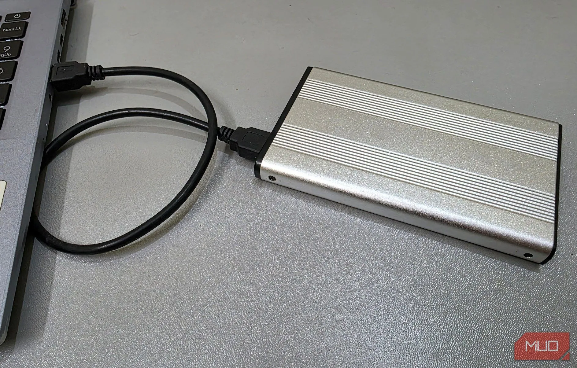 Một vỏ box ổ cứng ngoài đang kết nối với laptop, tượng trưng cho việc tạo kho dữ liệu bảo mật, mã hóa ổ cứng.