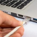 Người đàn ông cắm cáp Ethernet vào laptop chạy Windows