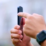 Người đàn ông cầm iPhone 15 Pro với ngón trỏ chạm nút tác vụ