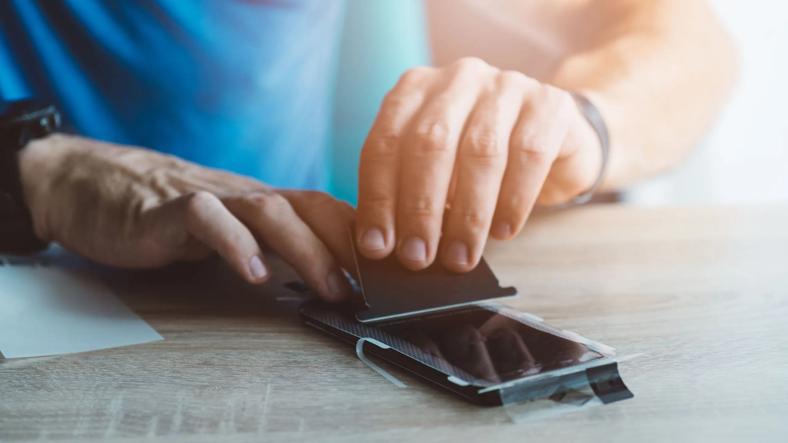 Người đàn ông đang dán miếng bảo vệ màn hình lên điện thoại iPhone
