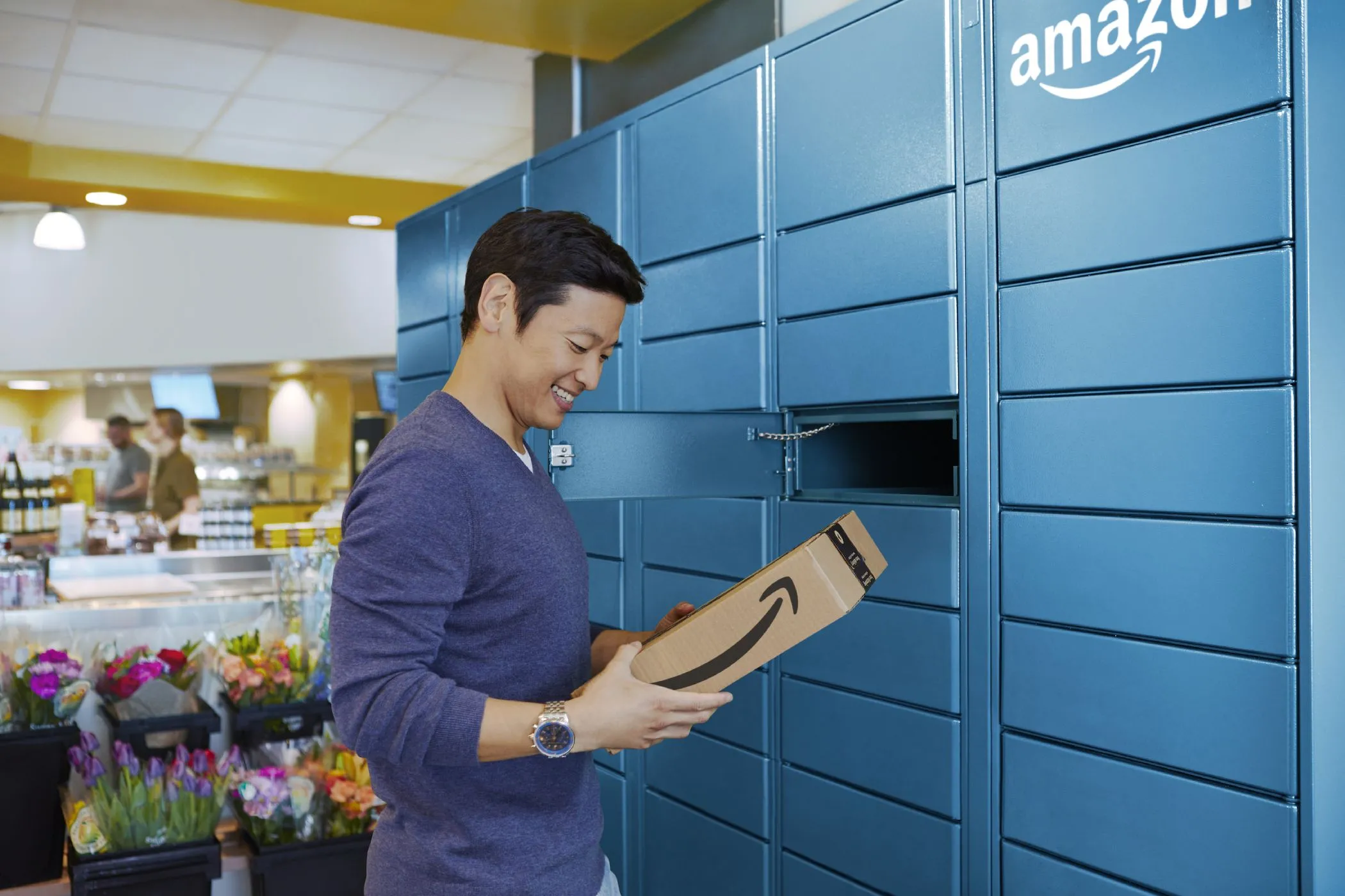 Người đàn ông đang lấy gói hàng từ tủ Amazon Locker, thể hiện giải pháp giao hàng thay thế an toàn và riêng tư.
