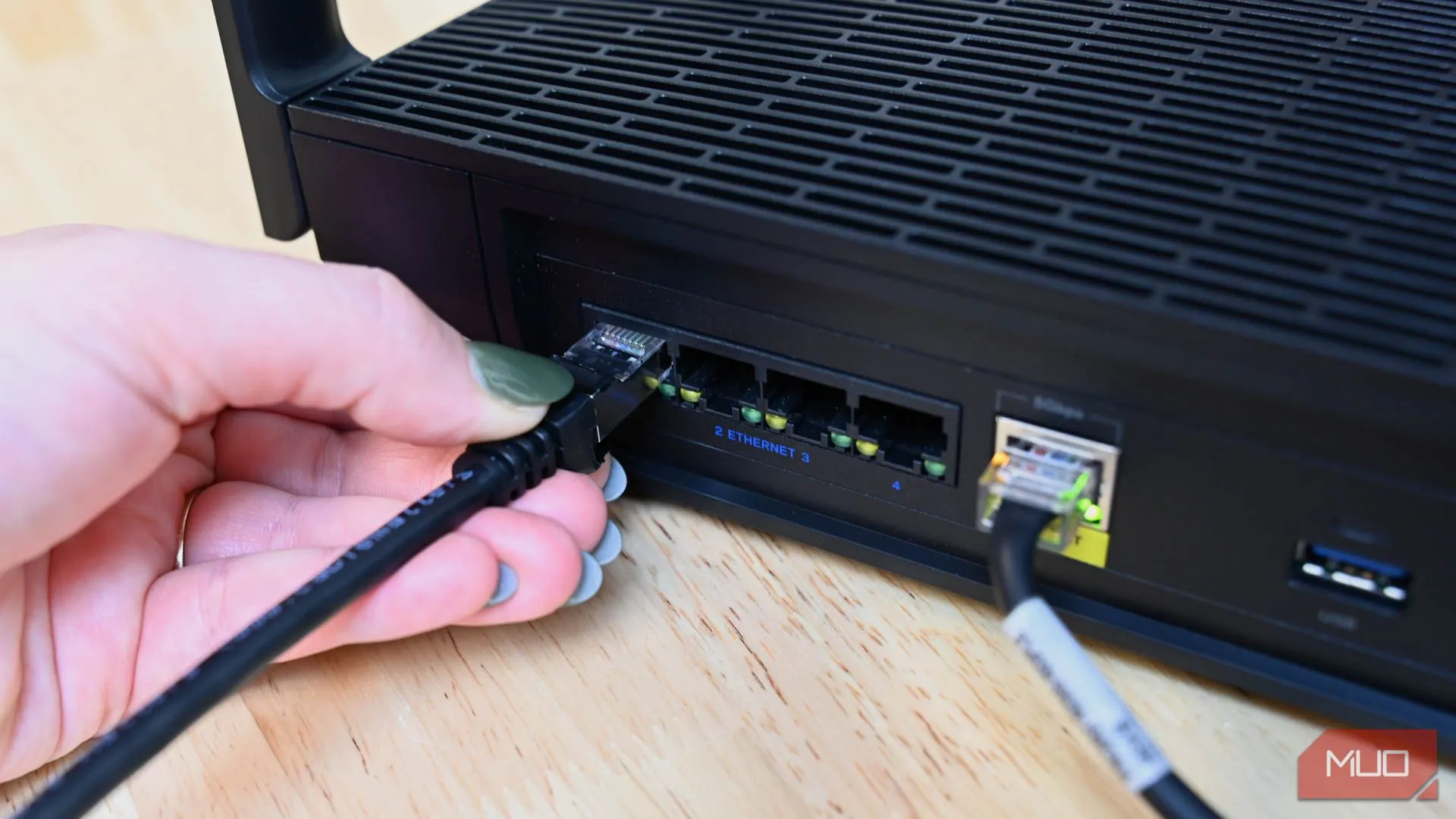 Người dùng cắm cáp Ethernet vào bộ định tuyến, minh họa giải pháp kết nối mạng có dây để tăng tốc.