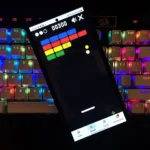 Người dùng đang chơi game Block Breaker trên điện thoại di động, ván điều khiển nằm ở cuối màn hình và các khối gạch đang được phá hủy