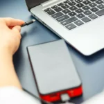 Người phụ nữ cắm cáp USB-C vào laptop, minh họa việc ngắt kết nối thiết bị khác khi sạc để tăng tốc độ