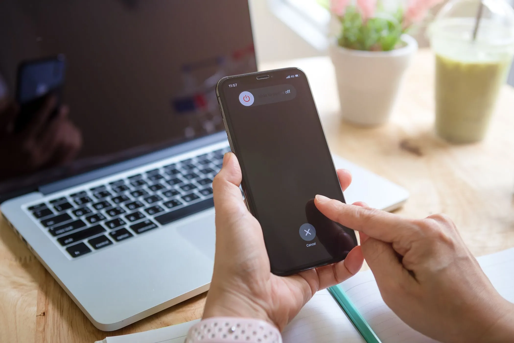Người phụ nữ đang tắt nguồn iPhone với MacBook ở phía sau
