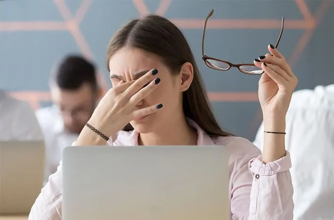 Người phụ nữ dụi mắt do mỏi mắt kỹ thuật số khi dùng màn hình Dark Mode