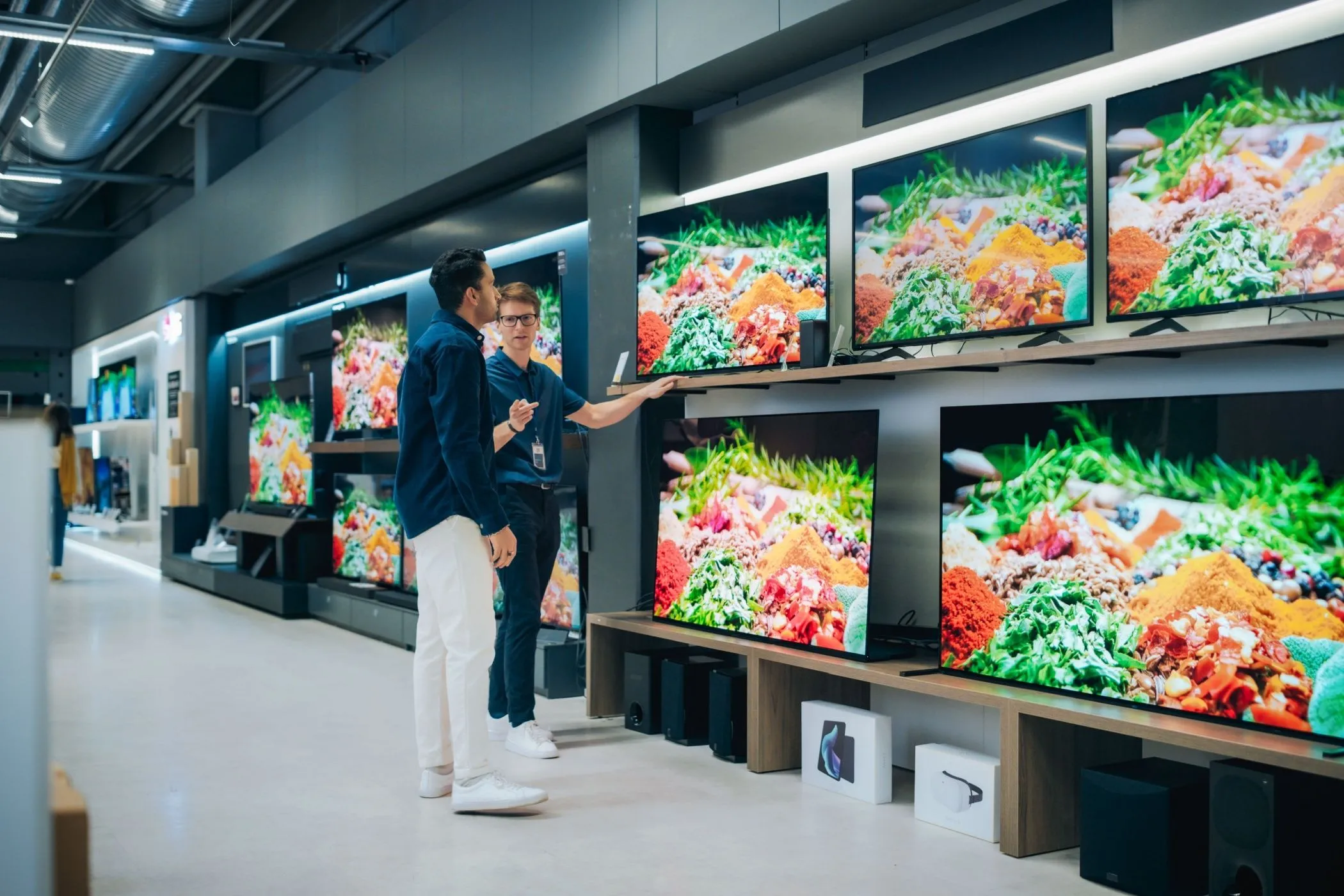 Nhân viên cửa hàng đang giới thiệu sản phẩm TV cho khách hàng, thể hiện trải nghiệm mua sắm cá nhân hóa và ưu đãi