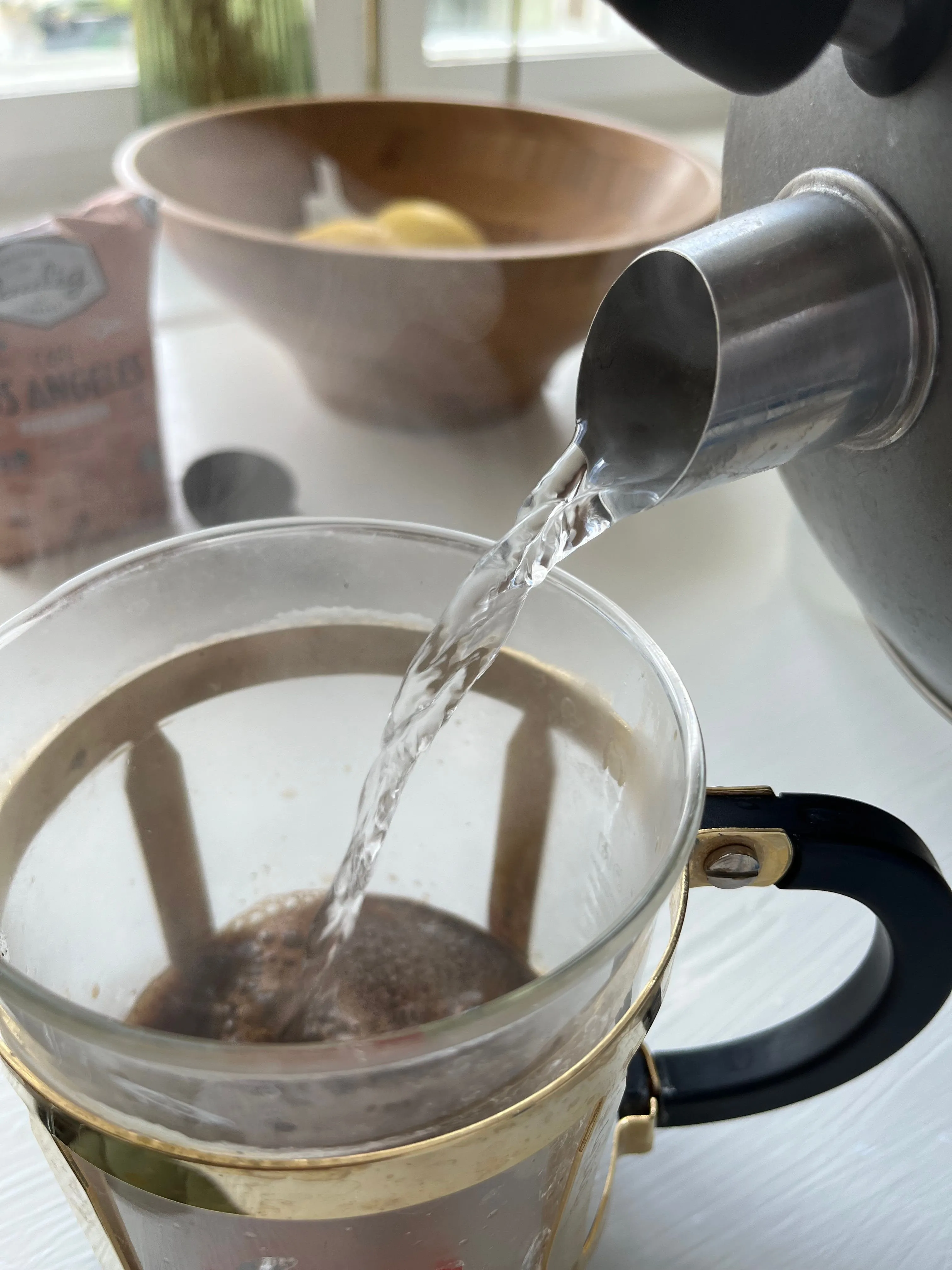 Nước được rót từ ấm vào bình pha cà phê, minh họa quy trình pha chế đồ uống tại nhà.