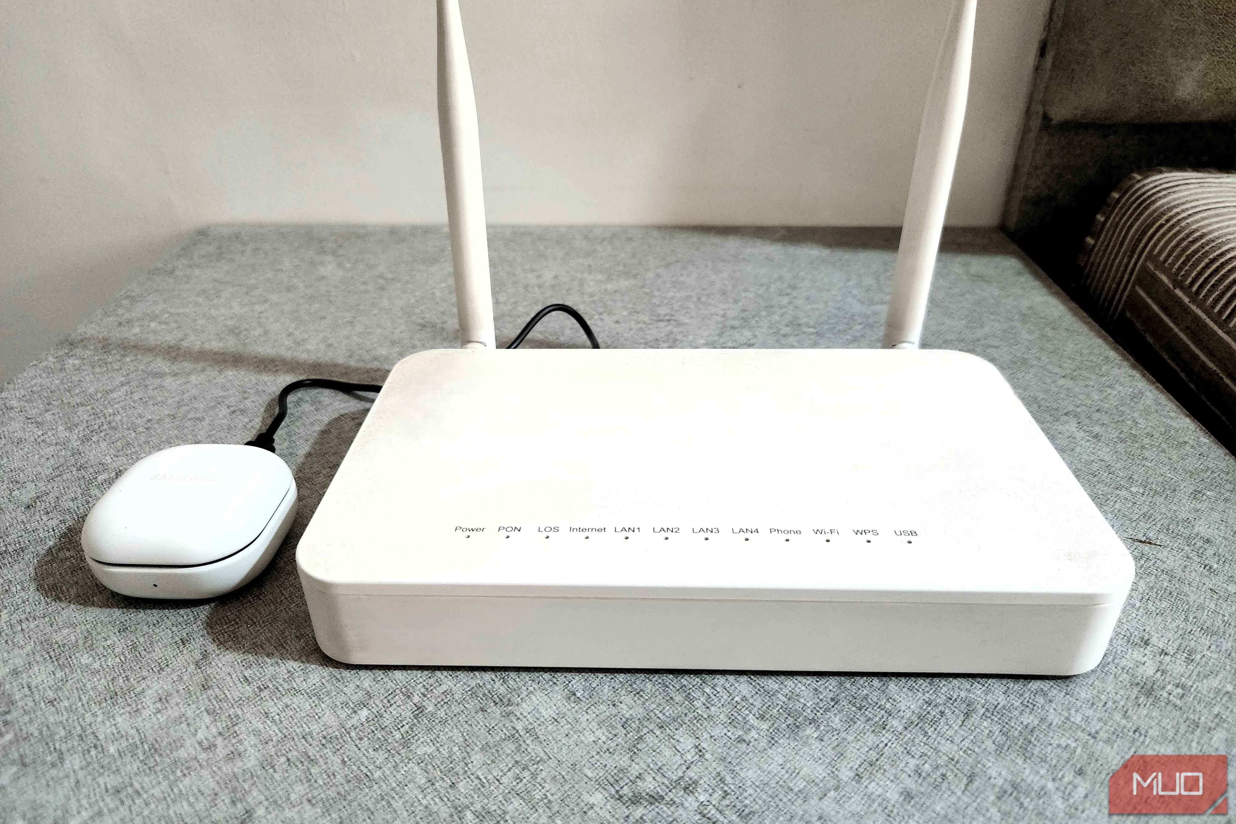 Tai nghe Bluetooth đang được sạc qua cổng USB của router, minh họa khả năng sạc thiết bị nhỏ