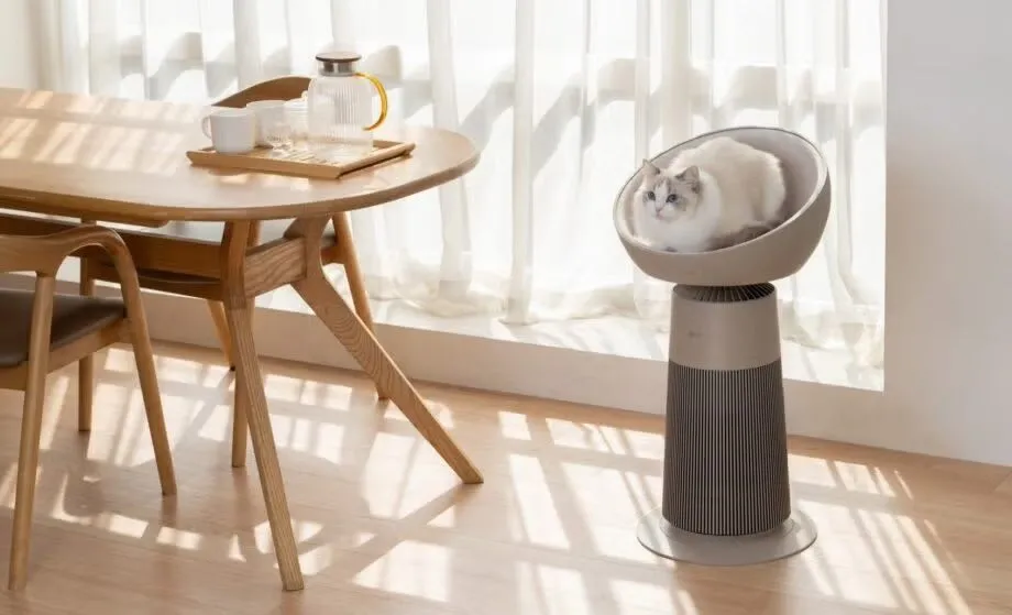 Tháp lọc không khí LG AeroCat Tower màu trắng với thiết kế hiện đại, một chú mèo đang nằm ngủ thoải mái trên phần đệm tròn ở đỉnh tháp.